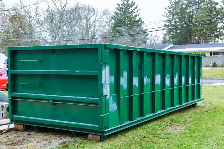 Tall green 30-yard roll-off dumpster resting on boards